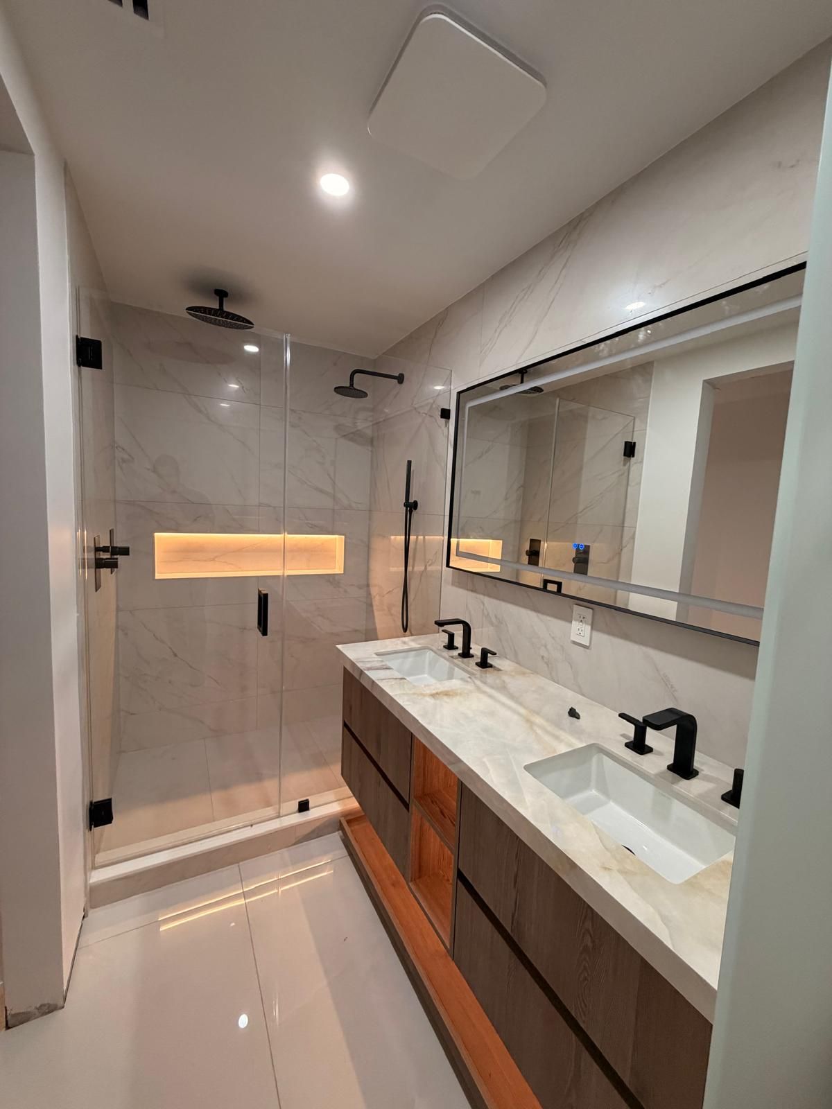 Completed bathroom with double vanity and glass shower